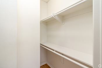 an empty closet with white walls and a white shelf